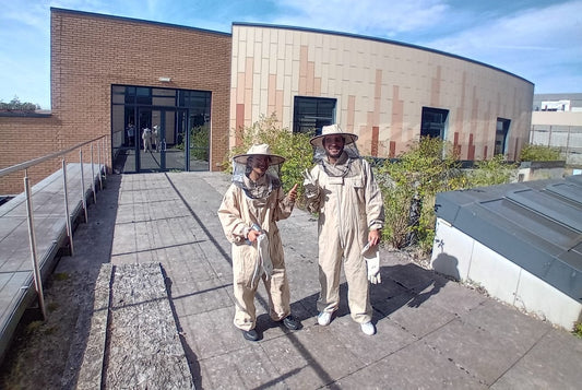 two new beekeepers in training on the roof of cardiff university smiling and gving the peace sign