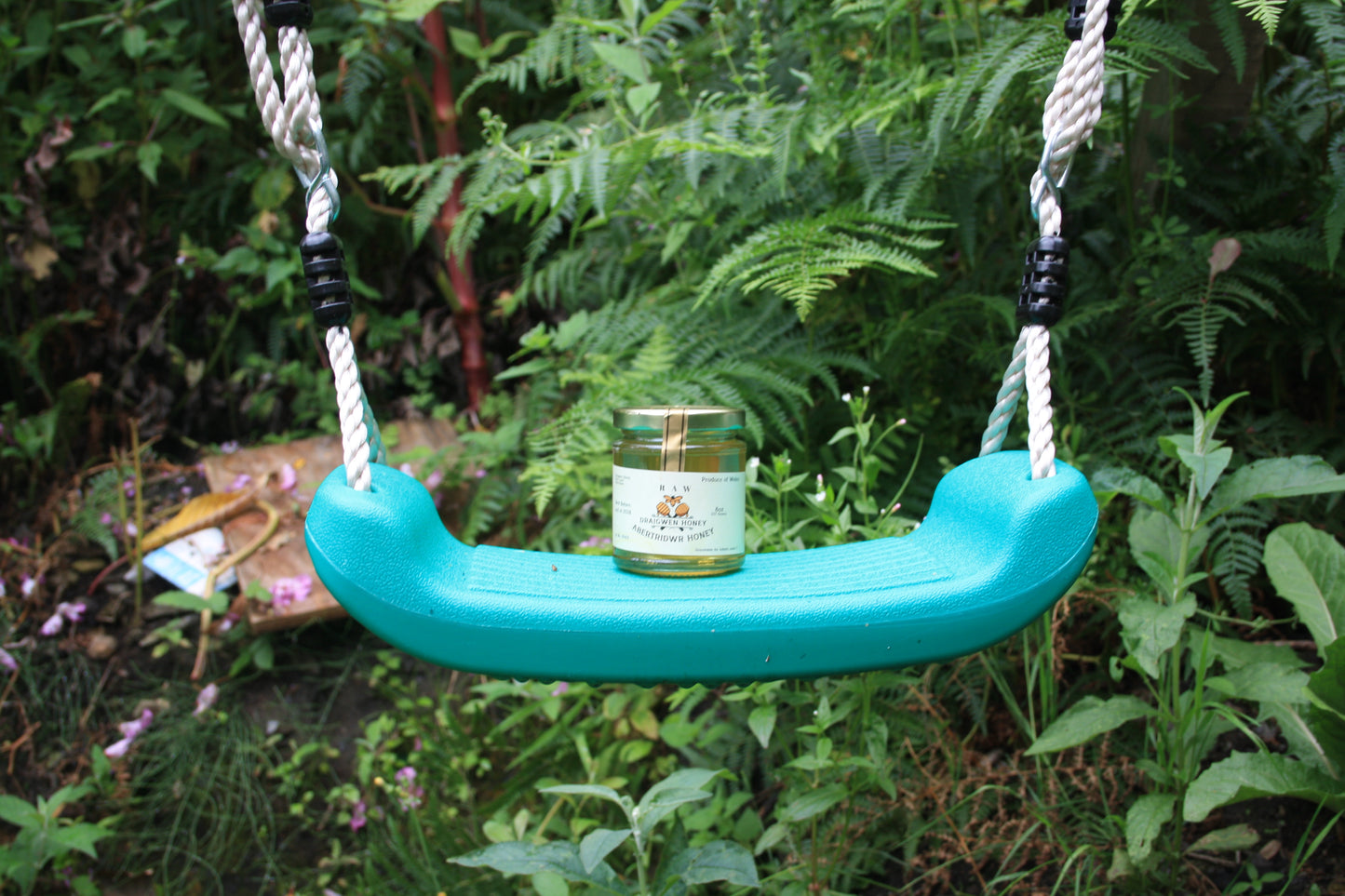 Teal swing seat with a jar of honey on a natural background
