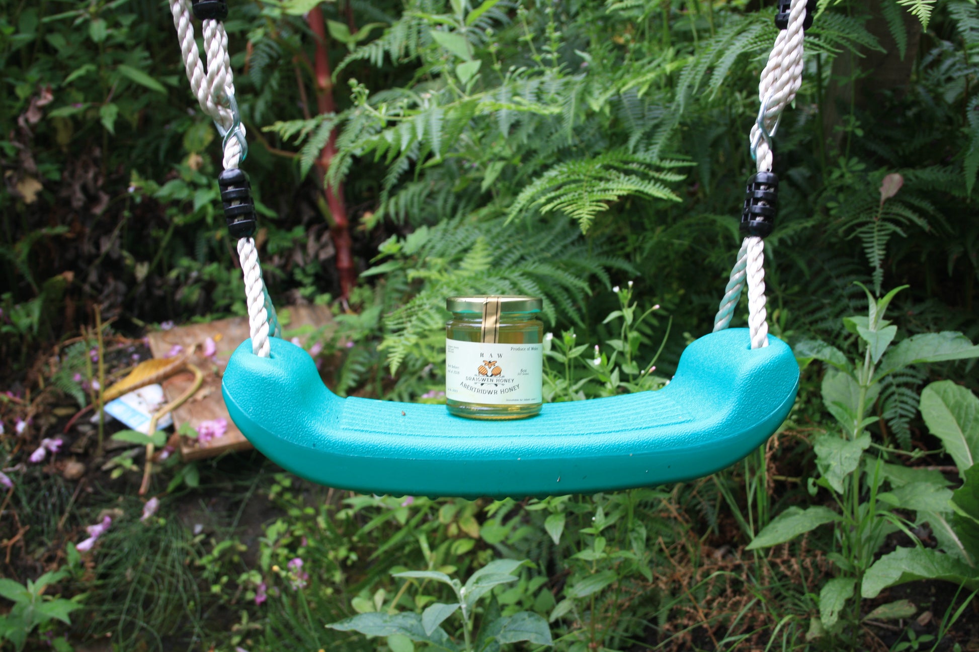 Teal swing seat with a jar of honey on a natural background
