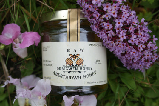 Jar of Draigwen Honey surrounded by pink flowers
